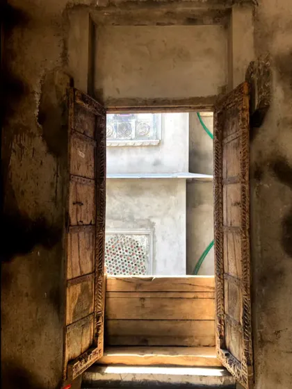 An old wooden door set in a rustic, weathered wall. The beauty of imperfection and the history embedded in such elements are concepts we explore in our wabi-sabi and fusion design projects.