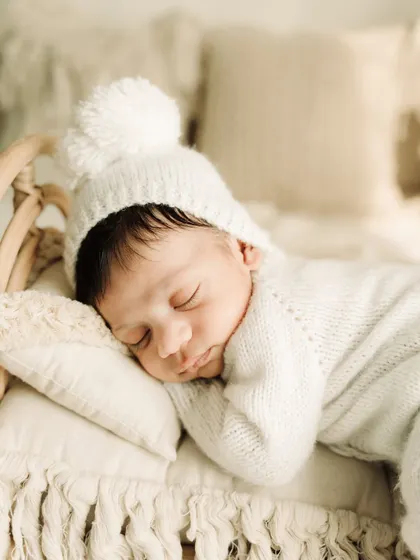 A close-up of the baby's sweet, sleeping face. The soft knit hat and gentle lighting make for a truly precious portrait.
