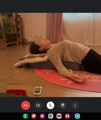 Even in an online session, we can achieve deep relaxation. Here, a student practices a supported restorative pose at home, allowing her nervous system to unwind and her body to release tension.