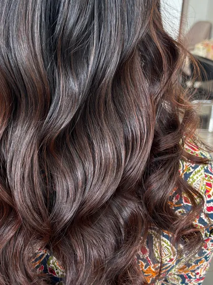 A close-up on the glossy waves, showing the subtle color variations that give this dark hair so much life and movement.