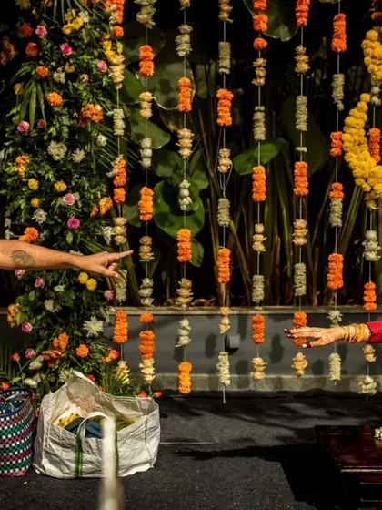 A playful moment between the couple during their traditional ceremony, set against a backdrop of hanging marigold flowers.