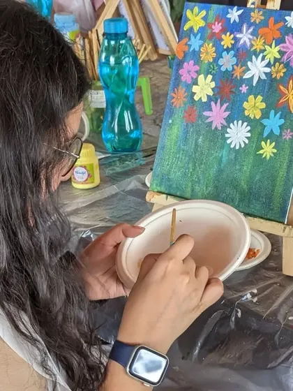 A participant working on a vibrant floral canvas painting. The bright colors and cheerful subject make for a joyful painting experience.