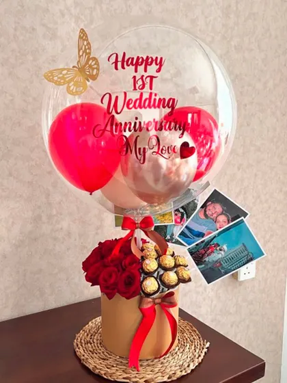 We love adding personal touches to our anniversary hampers. This first anniversary gift includes a box of red roses and Ferrero Rochers, a custom balloon, and even a few printed photos of the couple to make it truly unique.