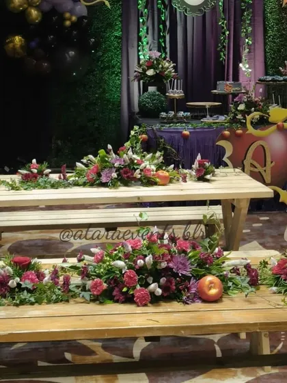 Floral arrangements on rustic wooden benches at our Descendants-themed party. The deep red and purple flowers, accented with apples, perfectly complement the "wicked" theme.