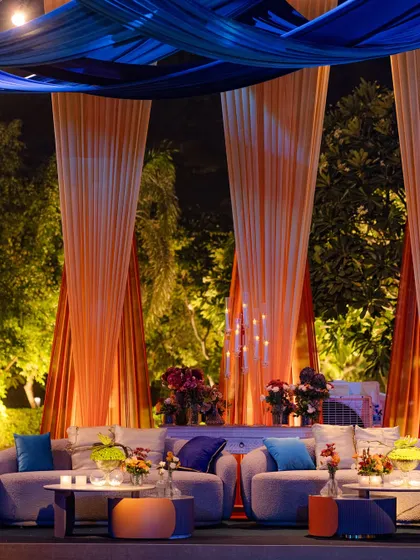 A lounge area from the 'Fire and Ice' event, where drapes of orange and blue fabric create a dramatic canopy. The comfortable seating is accented with pillows in the theme's colors, ensuring a cohesive look.