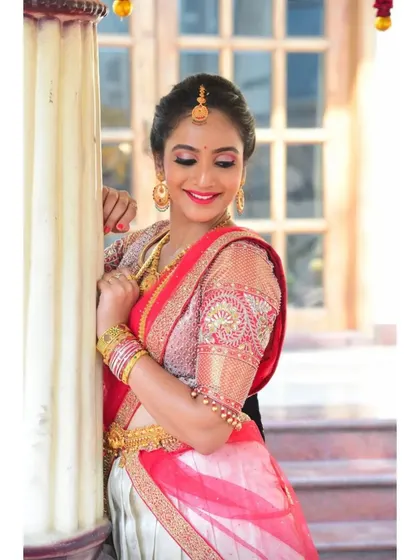 A beautiful portrait of the client in her white and red half-saree, giving a closer look at the intricate embroidery on the sheer sleeves of her blouse.