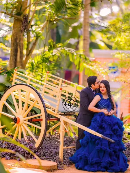 This pre-wedding shoot combined rustic and royal themes. The couple is styled in a blue gown and suit, posing with a traditional bullock cart for a unique photo opportunity.