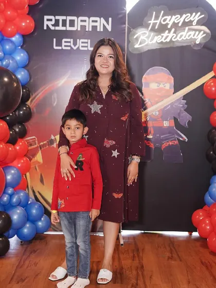 The birthday boy and his mom pose in front of our custom Ninjago "Level 6" birthday party backdrop.