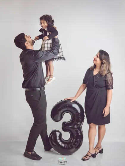 A third birthday celebration with the whole family. The dad lifting his daughter adds a dynamic and joyful element to this studio family portrait.