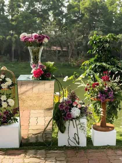 A collection of floral arrangements by the lake, using birdcages, pedestals, and vases to create a beautiful, multi-level display.