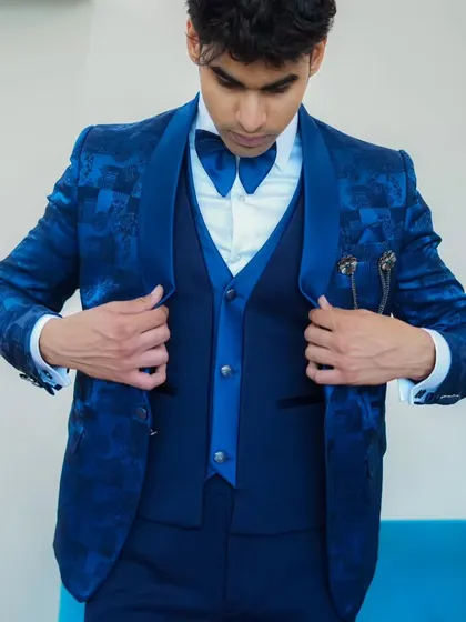 A model adjusting his royal blue patterned tuxedo, showing how comfortable and well-fitted our suits are.