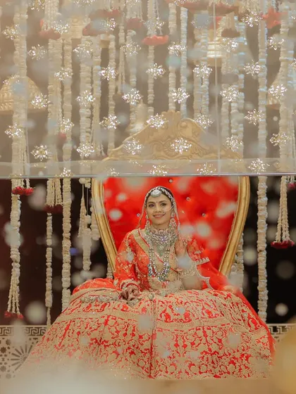A queen on her throne. This ethereal shot captures the bride seated in a regal chair, framed by a curtain of flowers, looking every bit the royal she is.