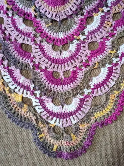 A detailed shot of the lacy, openwork sections of the Virus Shawl pattern. This design is not only visually stunning but also creates a fabric that is light and comfortable to wear.