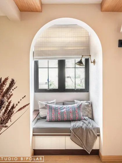 An arched niche with a built-in window seat creates a perfect, cozy reading nook. This architectural detail adds charm and functionality, making the most of the available space.