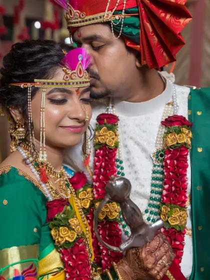 A tender kiss on the forehead, a classic romantic gesture captured after the wedding rituals.