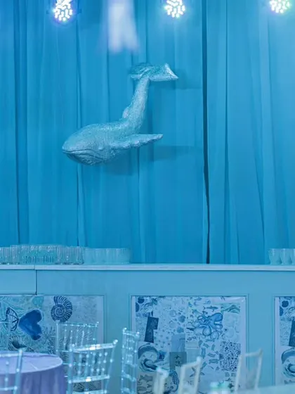 The bar area was transformed into a deep-sea scene with blue drapery and a majestic whale prop. Even functional areas of an event are styled to maintain the thematic illusion.