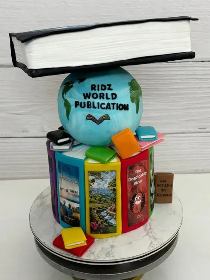 A different angle of the topsy-turvy book cake, showing the colorful, edible book spines and the globe.