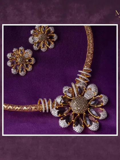 A matching set that embodies elegance and strength. The bold, floral necklace with its dark, smoky stones and diamond accents is paired with matching stud earrings for a complete, show-stopping look.