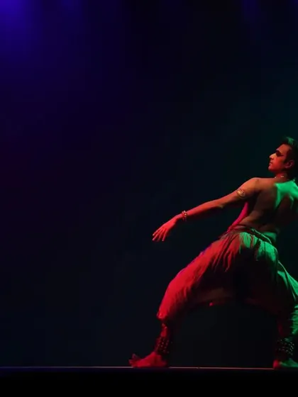 A dynamic pose from 'Shivanjali', with dramatic lighting creating a powerful silhouette. The energy of the dance is captured in this single frame.