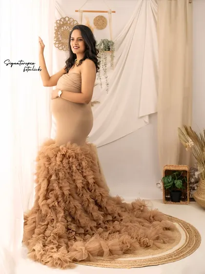 A full-length portrait by the window, showcasing the dramatic train of the ruffled gown against the soft curtains.