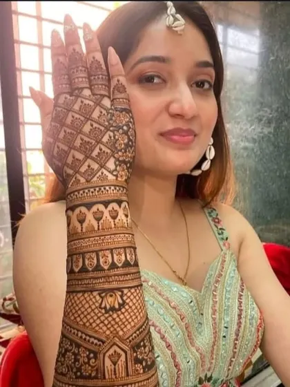 A happy client showing her beautiful, intricate bridal mehndi, which covers her arm from fingers to elbow.