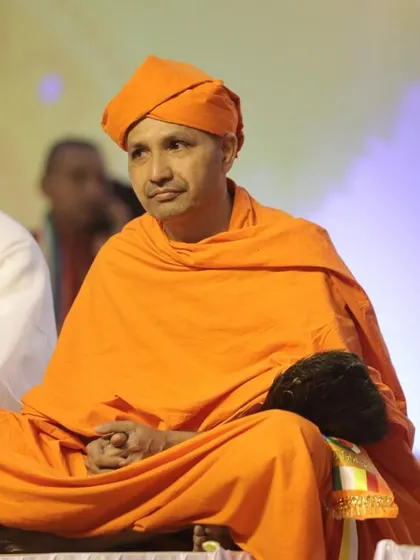 A spiritual leader seated peacefully on stage during the Lord Mahavir foundation day event. We create a serene and respectful environment for all our spiritual gatherings.