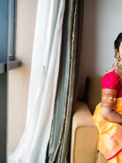 The bride seated by a large window, looking out thoughtfully. This portrait uses natural light to create a soft and contemplative mood.