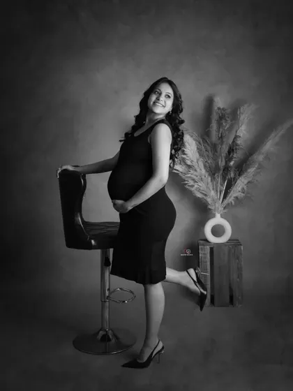 A playful and happy pose captured in a classic black and white studio setting. This shows that monochrome photos can be just as joyful and full of personality.