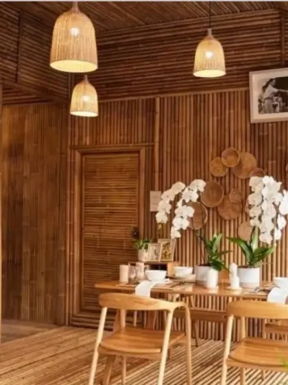 A dining room fully paneled with bamboo, creating an immersive, natural environment. Our simple, bell-shaped pendant lights hang above the table, their warm glow enhancing the rich tones of the bamboo walls and floor. This demonstrates our ability to execute complete interior concepts.
