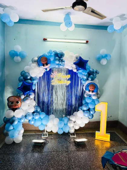 A full view of the Boss Baby themed room decoration. The central balloon ring is complemented by balloon clusters on the ceiling and a light-up marquee number '1'.