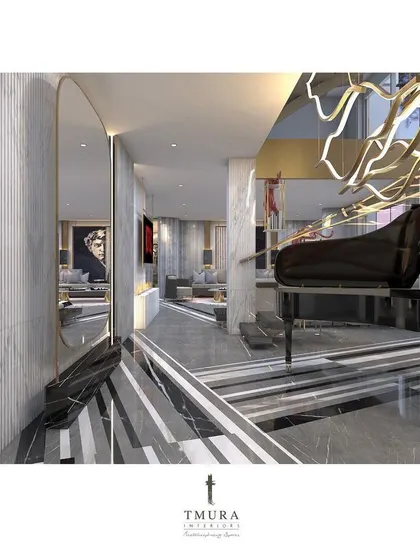 A grand piano is positioned at the base of the floating staircase, reflected in a large, arched mirror. The entire composition, including the striped marble floor and sculptural chandelier, creates an unforgettable foyer.