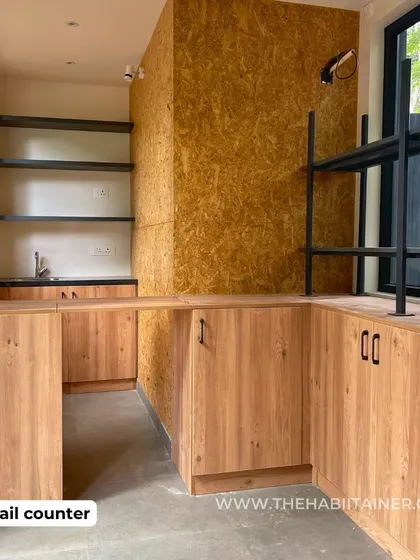 The interior of the TATA COFFEE store, showing the custom-built retail counter made from light wood. The space is designed for operational efficiency, with an OSB accent wall adding a touch of rustic texture.