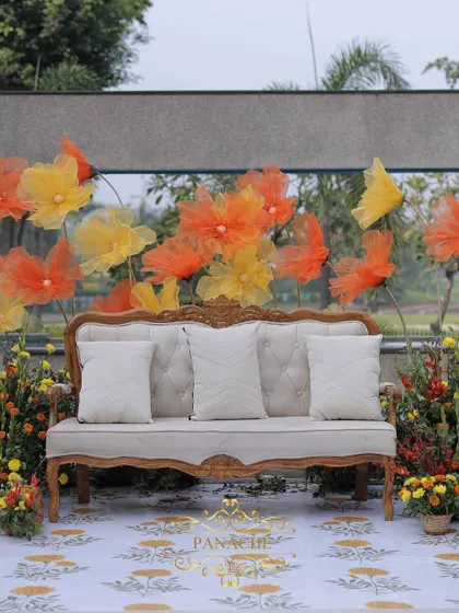 A frontal view of the couple's seating, showcasing the printed carpet and the whimsical organza flower backdrop.