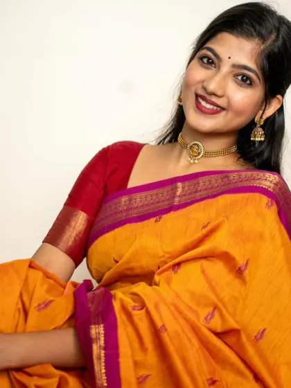 A festive portrait for Kannada Rajyotsava, wearing a bright yellow and pink saree. The close-up shot captures the celebratory spirit with a warm smile and traditional attire.