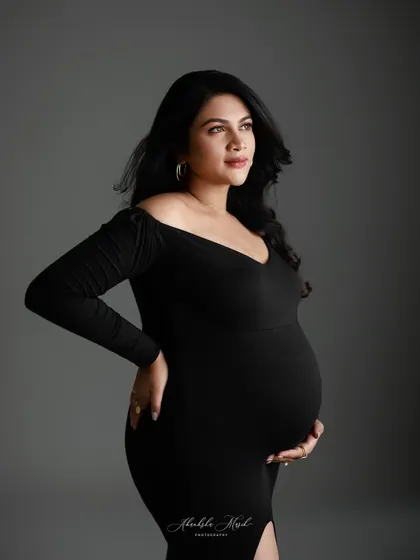 A classic and sophisticated portrait in a simple black gown, where the focus is entirely on the mother's confident gaze and beautiful form.