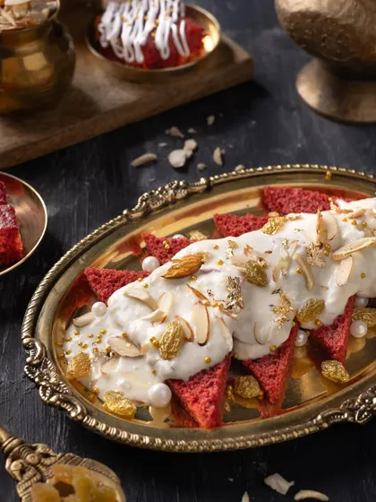 A luxurious fusion dessert, Red Velvet Shahi Tukda, plated on an ornate golden tray with a dark, moody background to emphasize its richness.