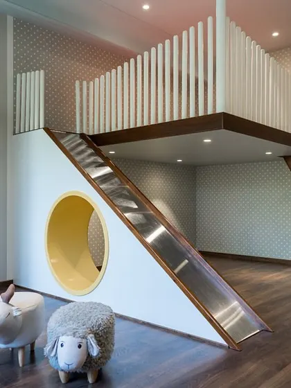 We believe children's rooms should be spaces for imagination to take flight. This custom-designed room features an elevated bed with an integrated slide and a cozy nook below, encouraging both play and rest. The use of soft hues and whimsical patterns creates a joyful yet calming atmosphere for growth and creativity.