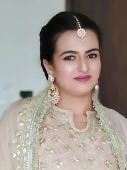 The front view of the client with her hair styled in a chic bubble braid. The hair is pulled back neatly, highlighting her makeup and maang tikka.