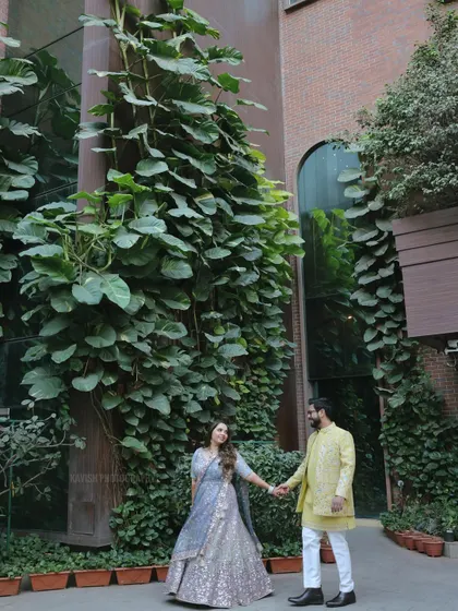 A romantic wedding portrait of the couple holding hands, framed by the lush greenery and modern architecture.