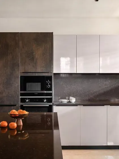 This kitchen combines rustic-finish dark cabinets with glossy white ones for a modern, high-contrast look. The large island is perfect for meal prep and gathering around. It’s a space designed for family life.