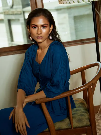 A closer portrait that captures the model's direct and confident gaze. The natural light beautifully highlights her features and the texture of the fabric.