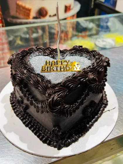 A heart-shaped chocolate cake with a silver glitter top, perfect for a birthday or anniversary.