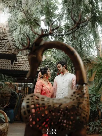 A creative portrait of a couple framed by a decorative deer sculpture, showcasing our eye for unique compositions.