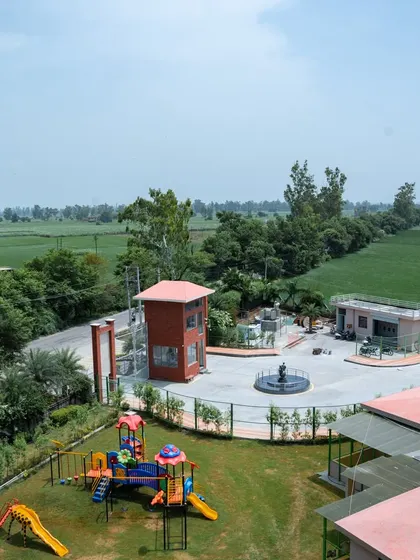 An aerial view of the Konark Academy campus, showing its integration with the surrounding lush green landscape. The layout includes a playground, parking areas, and a formal entrance with a water feature.