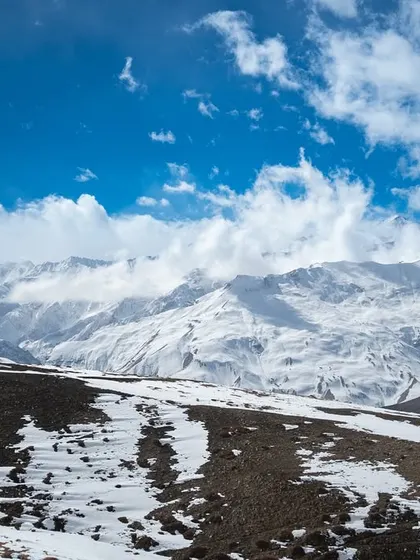 A collection of breathtaking landscapes from Spiti. These images feature the majestic snow-capped peaks, the turquoise river, and the dramatic, winding roads carved into the mountainside.