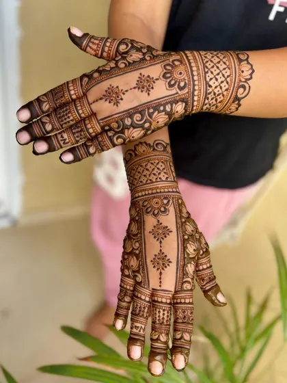 A wrist-length engagement mehendi with a central floral strip, bordered by traditional patterns.