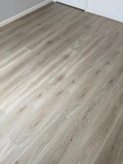 This close-up shows a light grey oak laminate floor, a perfect choice for a modern and understated look. It's an easy-to-clean and durable option that brings a cool, contemporary feel to any room.