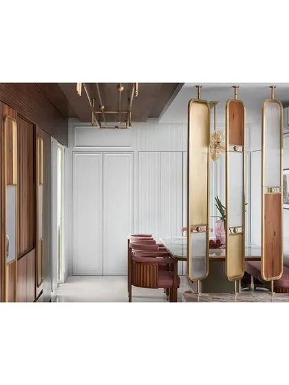 The dining area is separated from the living space by four elegant panels of wood, glass, and brass. This creates a sense of separation while maintaining the illusion of a larger, grander space.