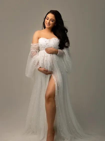 A portrait that focuses just on you and the miracle you're carrying. This mama-to-be looks absolutely radiant in a delicate, pearl-studded maternity gown, embodying pure joy.