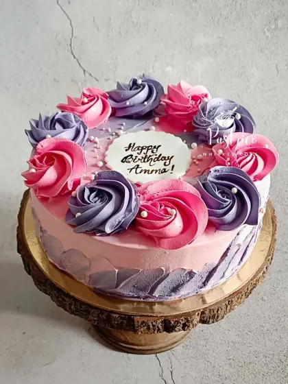 A beautiful floral cake with pink and purple roses, perfect for celebrating 'Amma's' birthday.